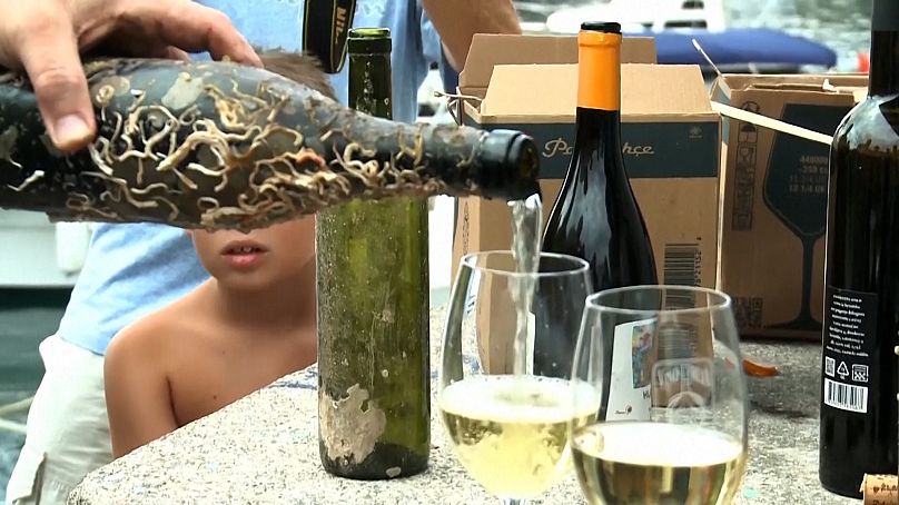 Une bouteille de vin immergée dans la mer est versée dans des verres dans la baie d'Ika