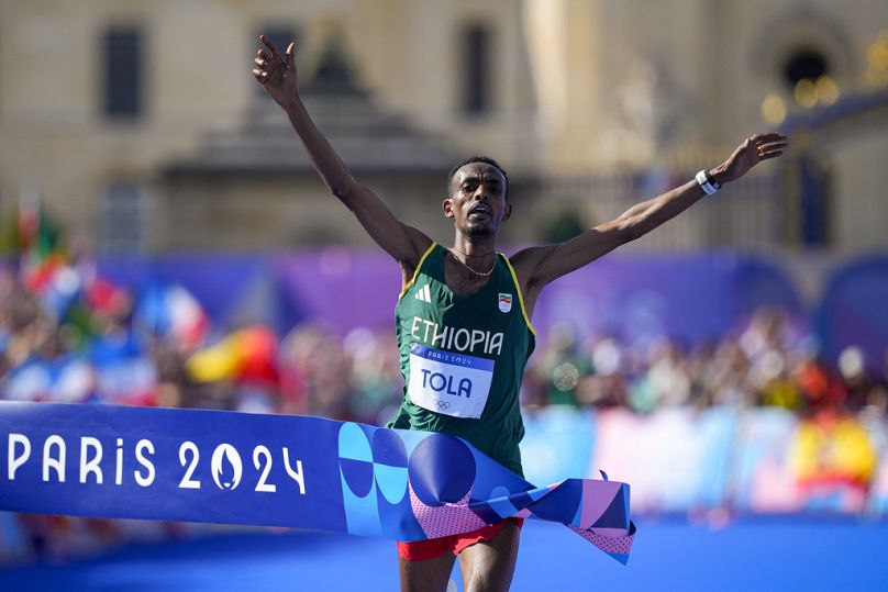 L'Éthiopien Tamirat Tola célèbre après avoir franchi la ligne d'arrivée pour remporter la médaille d'or à la fin de la compétition de marathon masculin aux Jeux olympiques de 2024