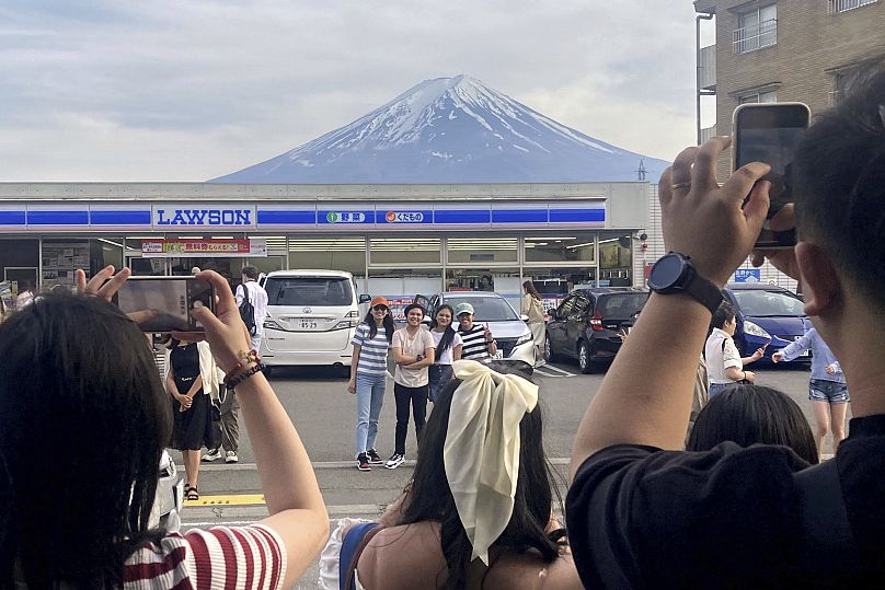 Des touristes prennent des photos devant le dépanneur Lawson, un lieu de prise de vue populaire offrant une vue pittoresque sur le mont Fuji en arrière-plan, le 30 avril 2024