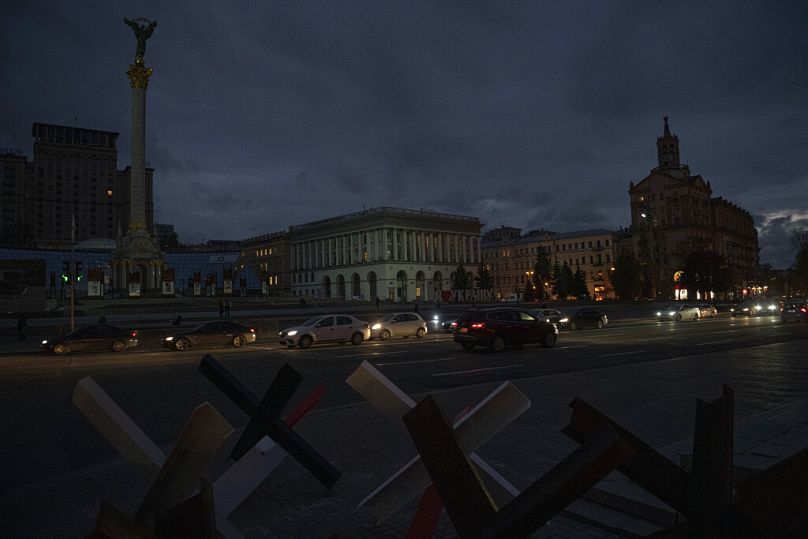 Des voitures passent sur la place de l'Indépendance au crépuscule à Kiev, en Ukraine, le lundi 31 octobre 2022.