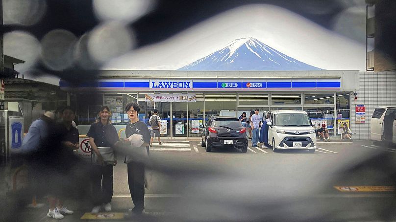 Le mont Fuji est vu à travers un trou sur un écran noir installé en face d'un dépanneur dans la ville de Fujikawaguchiko, préfecture de Yamanashi, centre du Japon, le 24 mai 2024.