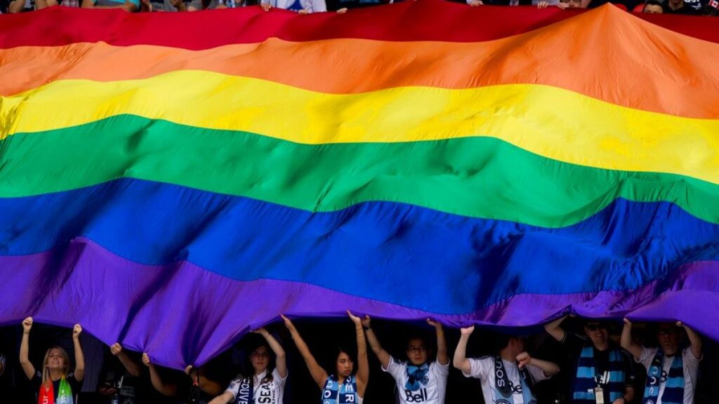 Fans support an oversized rainbow flag before the Vancouver Whitecaps play the Seattle Sounders in an MLS soccer game in Vancouver, British Columbia.