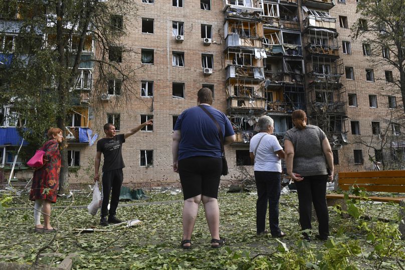 Les résidents d'un immeuble d'appartements endommagé après les bombardements du côté ukrainien se tiennent près du bâtiment à Koursk, en Russie, le dimanche 11 août 2024.