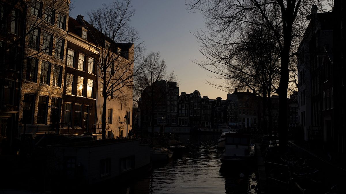 The setting sun bounces off a building in the Amsterdam city center skyline, Netherlands, Monday, Feb. 13, 2023.