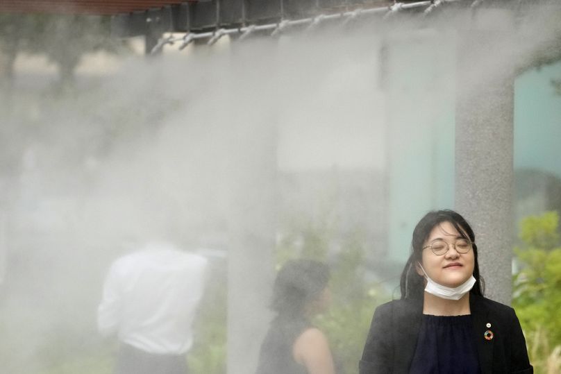 Les gens se rafraîchissent dans un endroit doté d'un brouillard rafraîchissant le 4 juillet 2024, à Tokyo. 