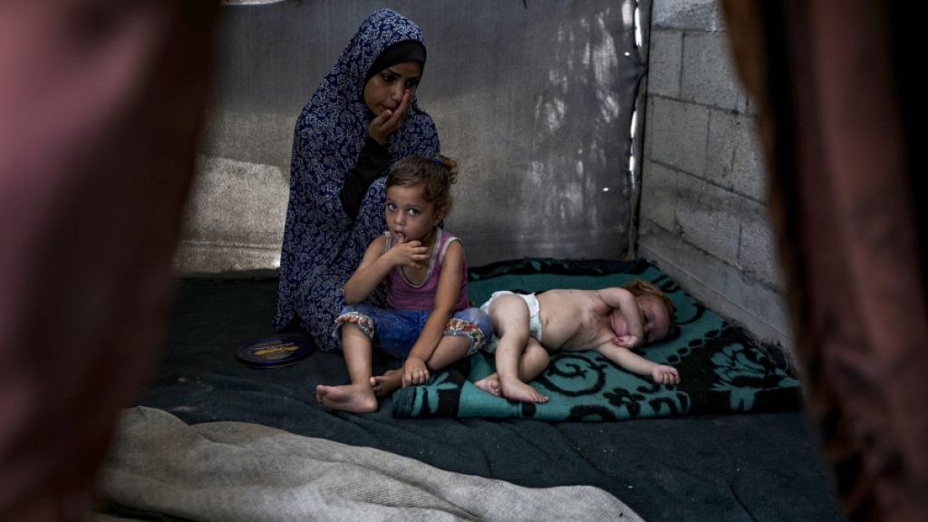 Palestinian Manar al-Hessi, who was displaced by the Israeli bombardment of the Gaza Strip, sits next to her children, at a makeshift tent camp in Deir al-Balah, central Gaza