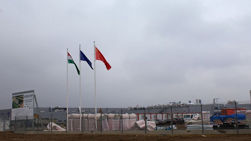Vue du chantier de construction à la périphérie de Debrecen, avec des drapeaux hongrois, européens et chinois flottant.