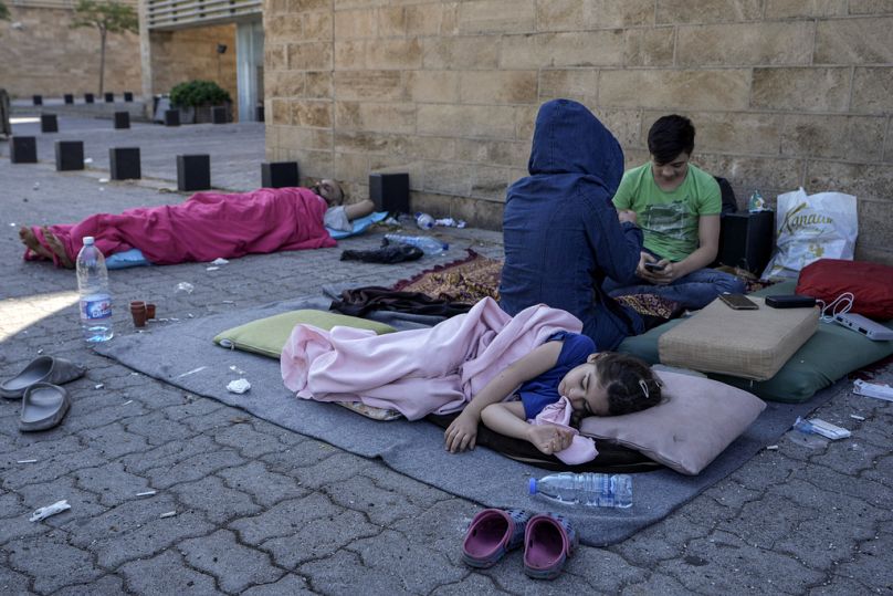 Une famille dort par terre dans le quartier de la corniche de Beyrouth après avoir fui les frappes aériennes israéliennes dans la banlieue sud de Dahiyeh, le dimanche 29 septembre 2024.