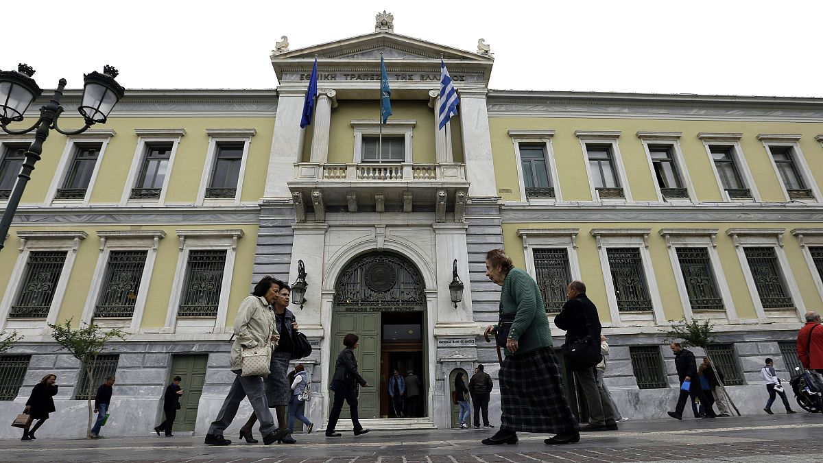 Pedestrians pass outside the headquarters of the National Bank of Greece in Athens. 30 October, 2015.