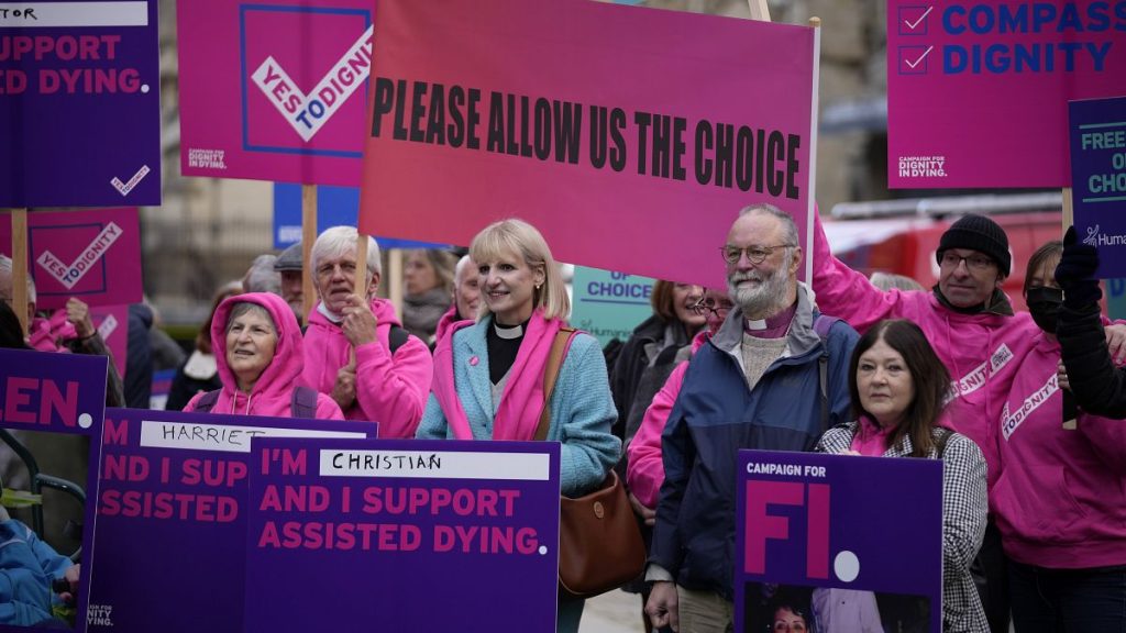 Campaigners holds signs as they rally for assisted dying access in October 2021 outside the Houses of Parliament in London.