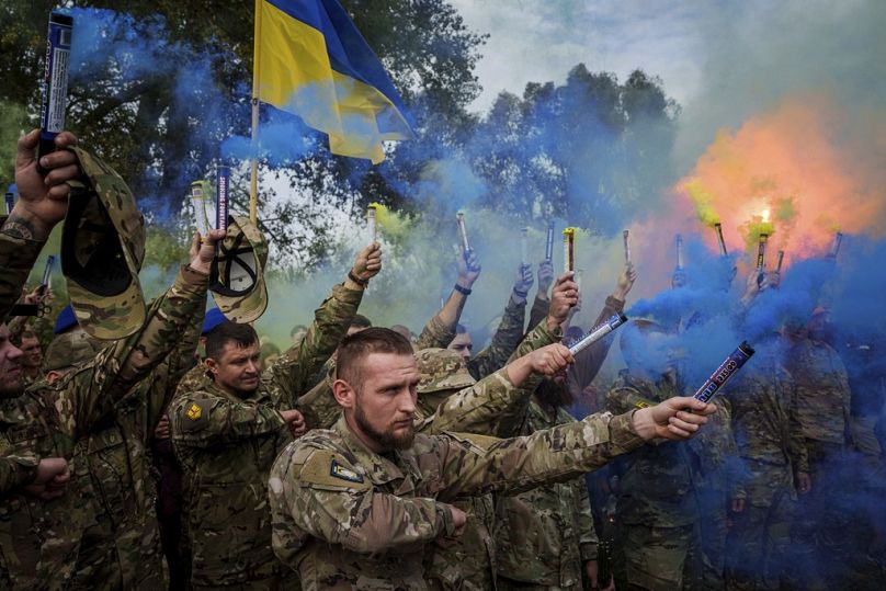 Des militaires ukrainiens allument des fusées éclairantes lors de la cérémonie funéraire du camarade Ihor Kusochek tombé au combat à Travkine, en Ukraine, le vendredi 4 octobre 2024.