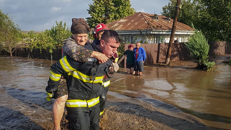Un secouriste transporte une femme dans les eaux de crue à Pechea, le 14 septembre 2024.