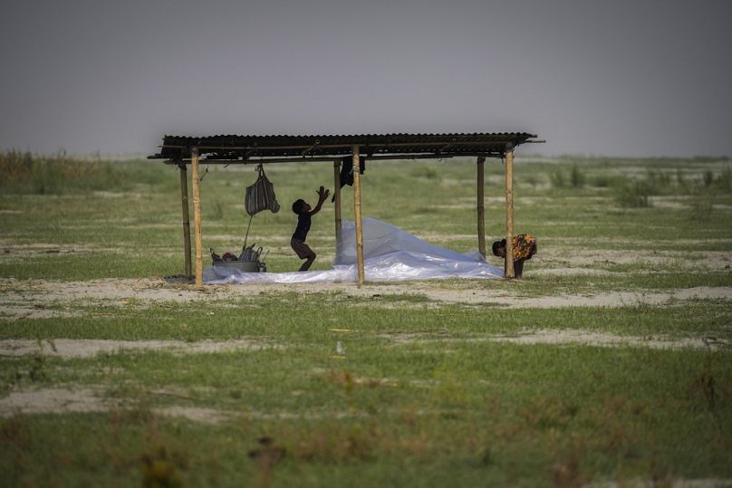 Des enfants jouent dans une ombre de fortune où les agriculteurs se reposent à Sandahkhaiti, un village insulaire flottant du fleuve Brahmapoutre dans l'Assam, en Inde.
