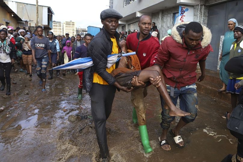 Des habitants sauvent une femme surprise sous la pluie dans le bidonville de Mathare à Nairobi, au Kenya.