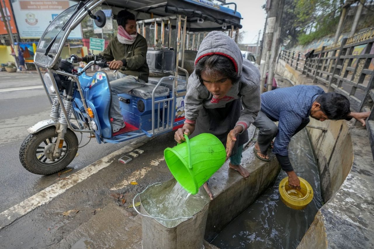 Des gens puisent de l’eau dans un drain à ciel ouvert à Guwahati, en Inde.
