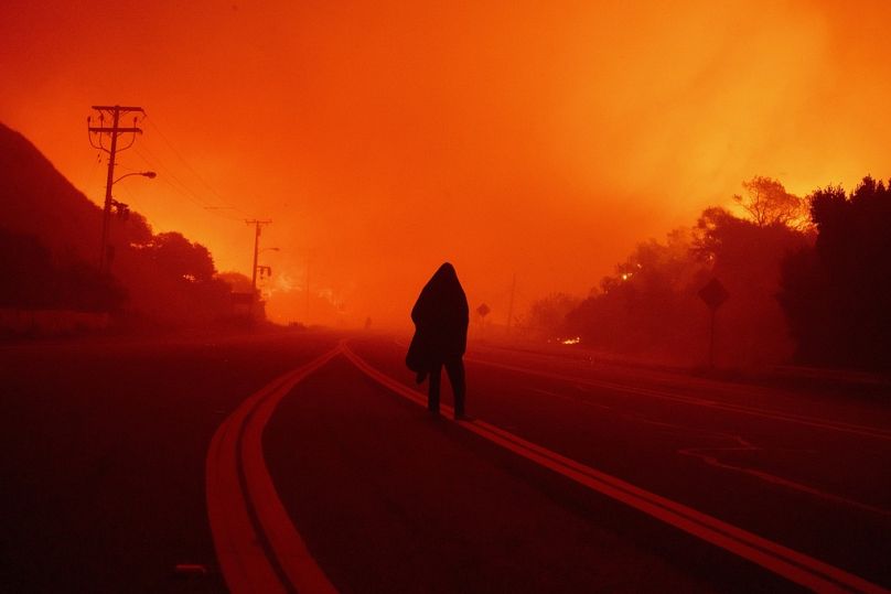 Une personne marche le long d’une route à l’approche de l’incendie de Franklin à Malibu, en Californie.