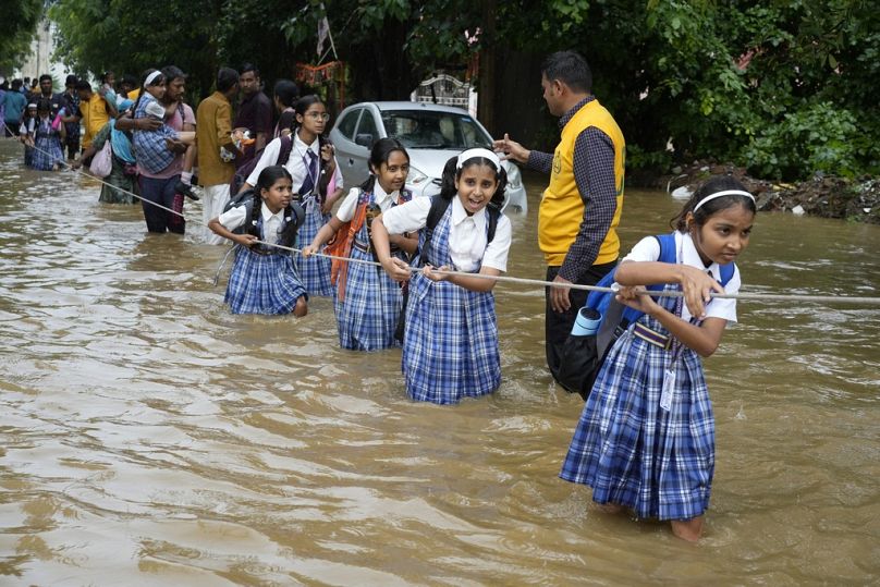 Des étudiants s'agrippent à une corde alors qu'ils traversent une rue inondée après de fortes pluies, sur le chemin du retour à Ajmer, en Inde.