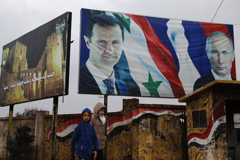 Des Syriens marchent devant des affiches du président syrien Bachar al-Assad et du président russe Vladimir Poutine à Alep, en Syrie, le jeudi 18 janvier 2018.
