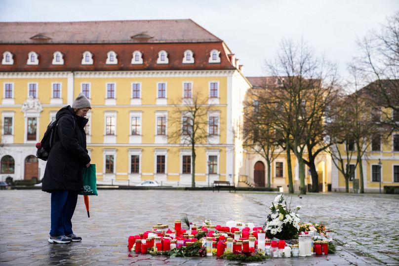 Une femme se tient à côté de fleurs et de bougies déposées près de la cathédrale de Magdebourg, après qu'une voiture ait percuté une foule d'une marque de Noël vendredi soir, à Magdebourg, en Allemagne,