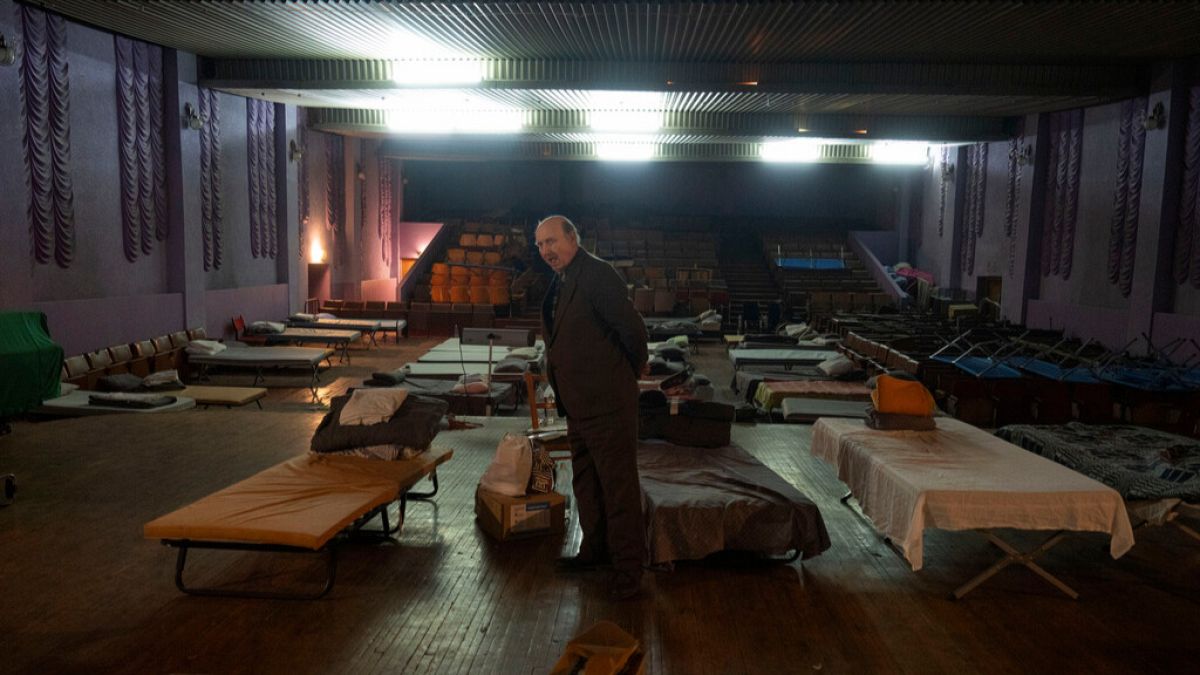 A man waits for evacuation to western Ukraine as he stands by a bed in a city theatre that hosts refugees running from Russian offensive in the Donetsk region, in Pavlohrad.