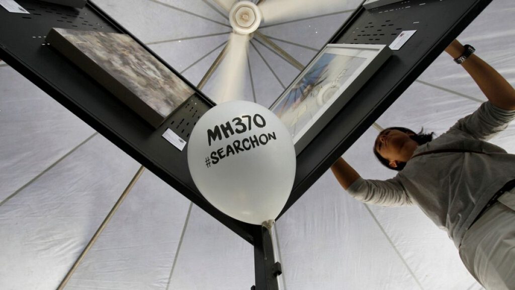 A man arranges artwork for an exhibition marking the Day of Remembrance for MH370 event in Kuala Lumpur, Malaysia on Saturday, March 4, 2017.