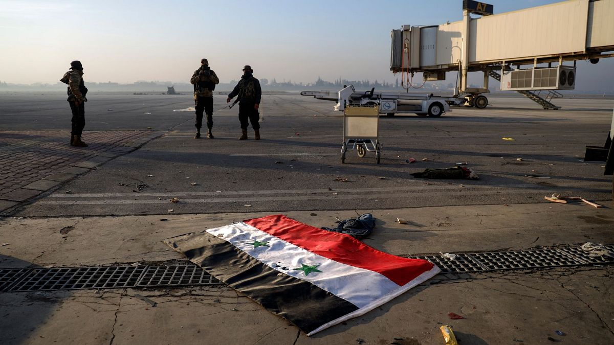 Syrian opposition fighters stand atop a seized Syrian Air Force fighter plane at the Hama military airport, Syria, Friday 6 Dec 2024.