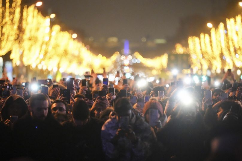 Les fêtards regardent un spectacle de lumière projeté sur l'Arc de Triomphe alors qu'ils célèbrent le Nouvel An sur les Champs Elysées, à Paris, France, le mercredi 1er janvier 2025.