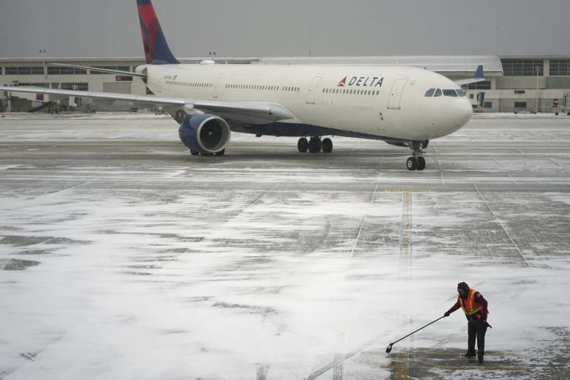 Un travailleur déblaye la neige d'une aire de trafic avant de guider un avion de Delta Air Lines à l'aéroport métropolitain du comté de Wayne de Détroit à Romulus, Michigan, le lundi 6 janvier 2025.