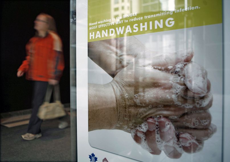 Un piéton passe devant une pancarte encourageant le lavage des mains afin de réduire la transmission des infections à Ottawa, le 30 avril 2009.
