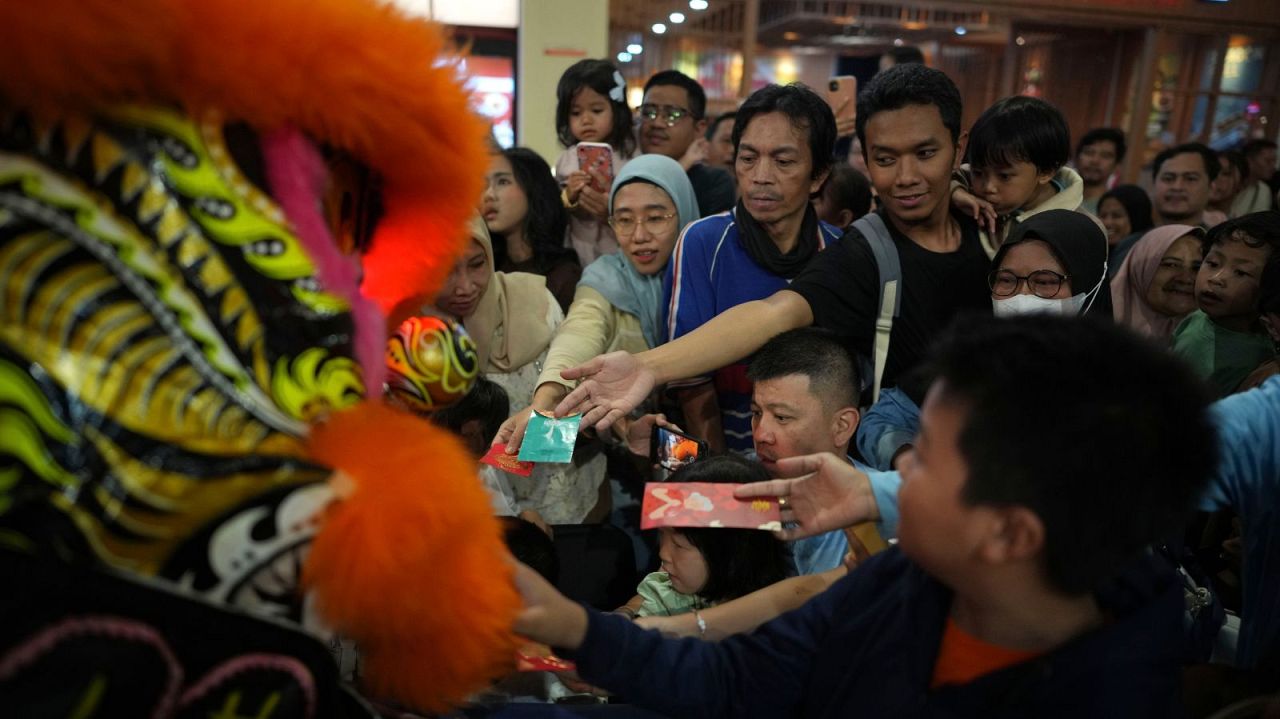 Les gens donnent à Hóngbāo, une enveloppe contenant de l'argent traditionnellement donné pendant les vacances chinoises ou pour des occasions spéciales, aux membres du Dragon Dance Club Naga Merah Putih