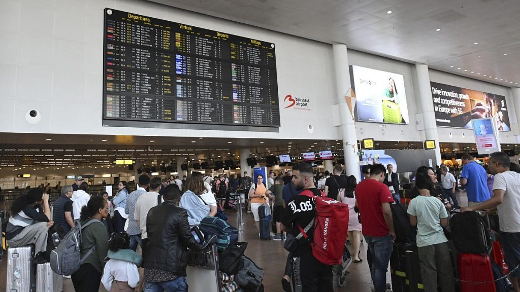 Travelers wait for information in front of a departure board at Brussels International Airport in Brussels, 19 July, 2024