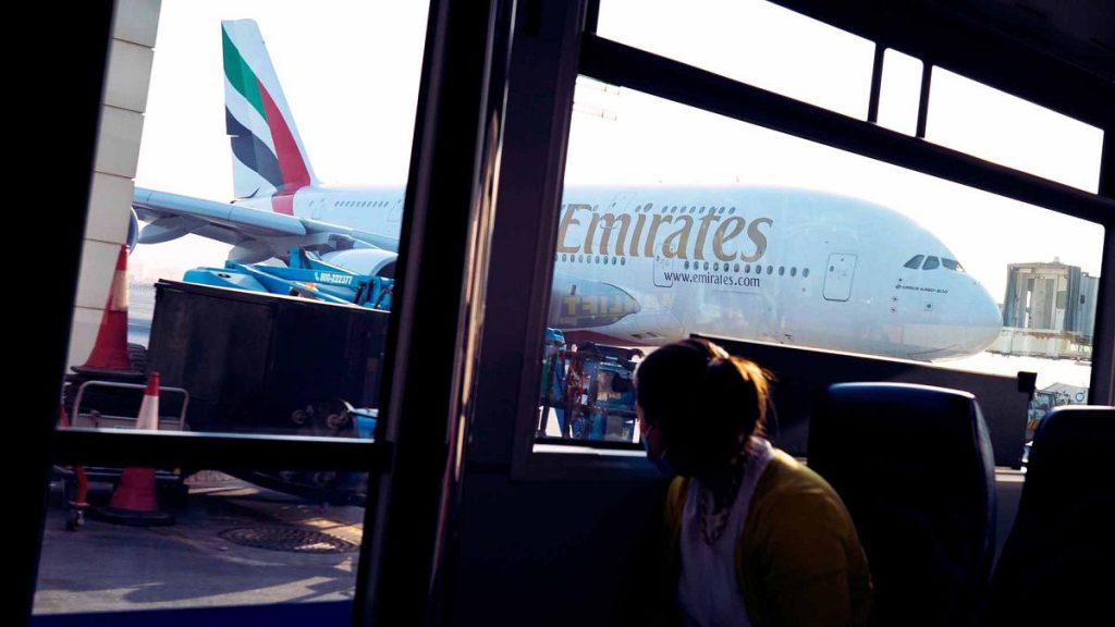 A woman in a bus looks out at an Emirates Airbus A380 jumbo jet at Dubai International Airport in Dubai, United Arab Emirates, Friday, Sept. 9, 2022.