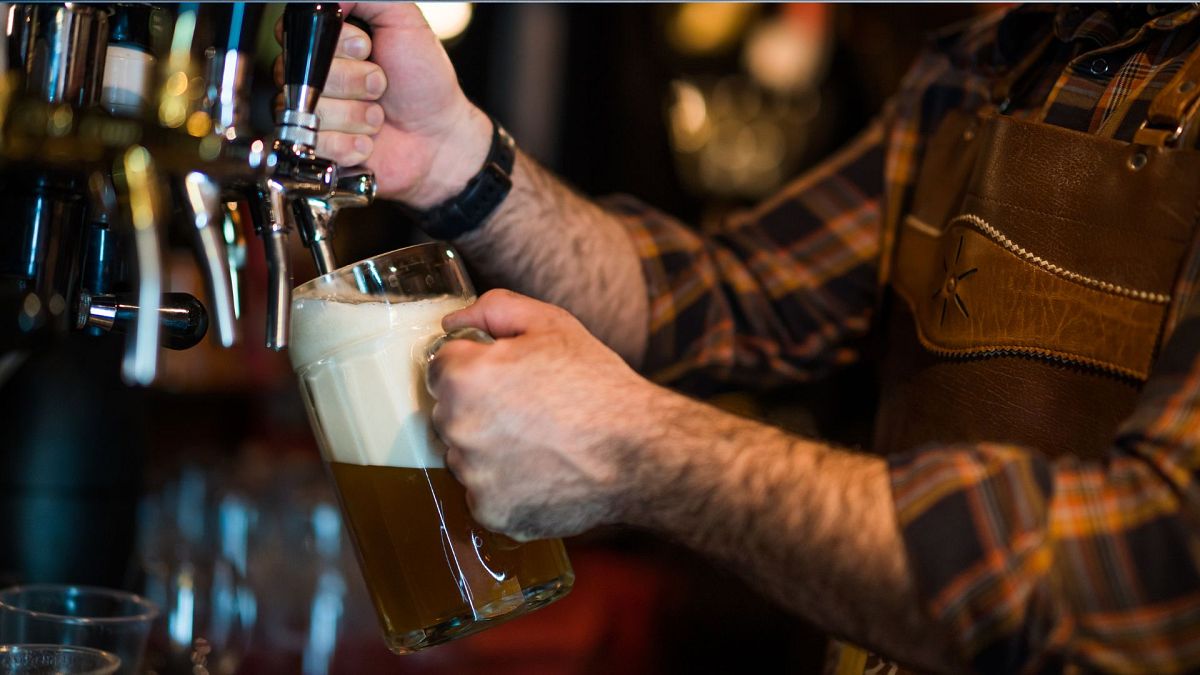 Close up photo of a bartender pouring beer into a beer glass at a pub.