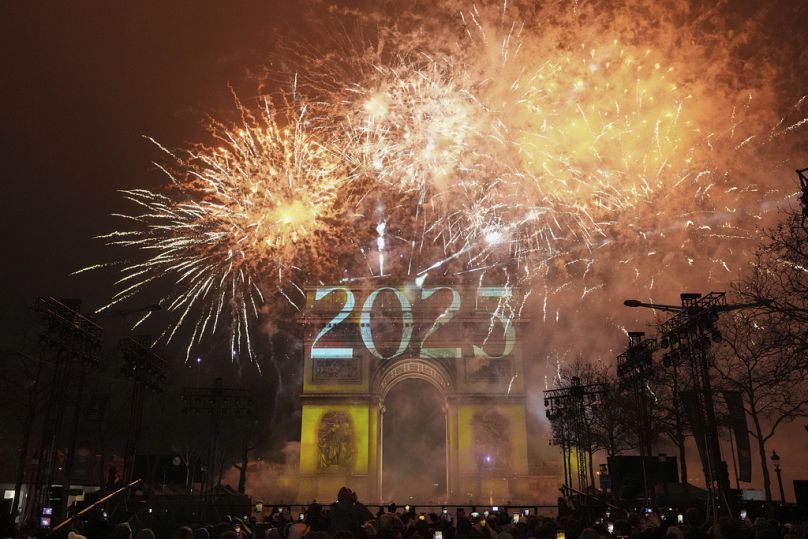 Un spectacle de lumière est projeté sur l'Arc de Triomphe alors que des feux d'artifice explosent lors des célébrations du Nouvel An sur les Champs Elysées à Paris, France, le mercredi 1er janvier 2025.