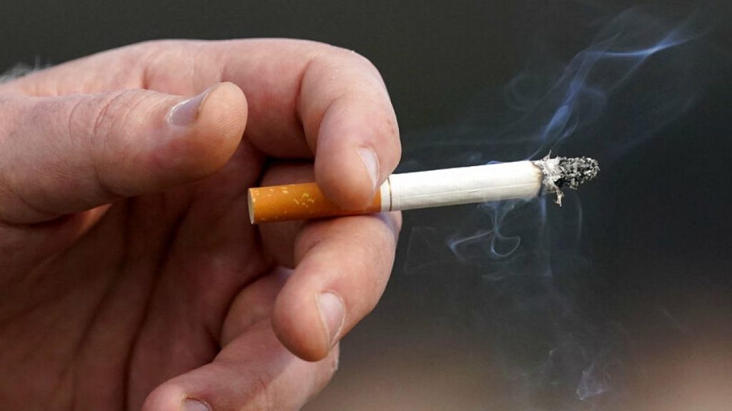 A man holds a lit cigarette while