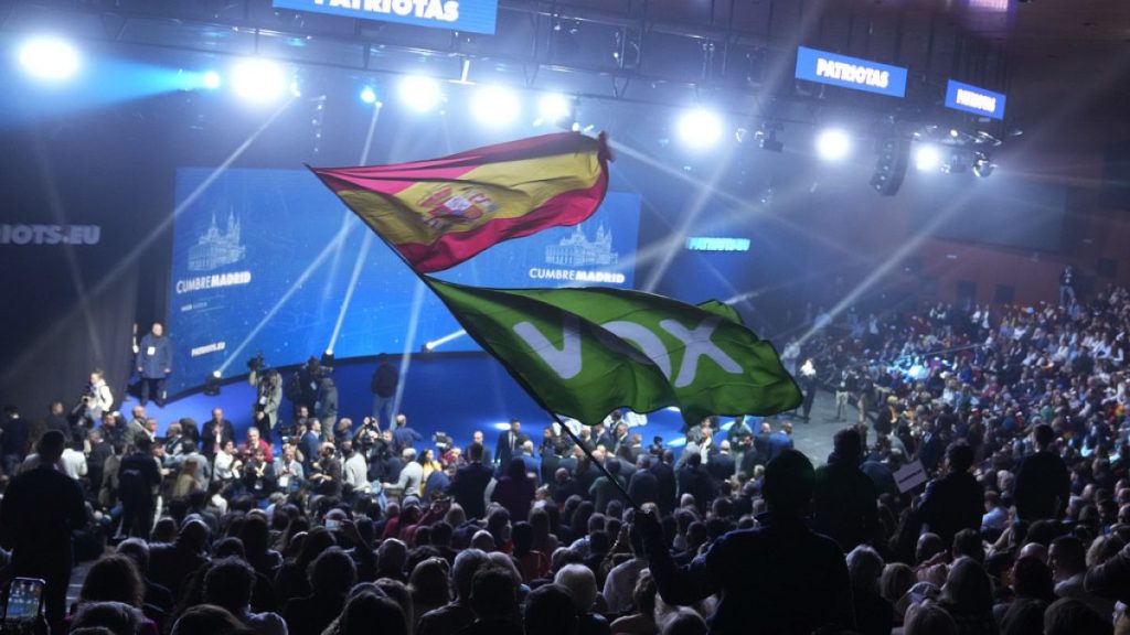 A Spanish flag and a Spanish far-right VOX party flag are waved during the far-right Patriots for Europe summit in Madrid, Spain, Saturday, Feb. 8, 2025. (AP Photo/Paul White)