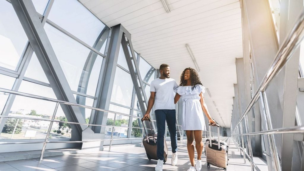 An African-American couple wander through an airport with suitcases