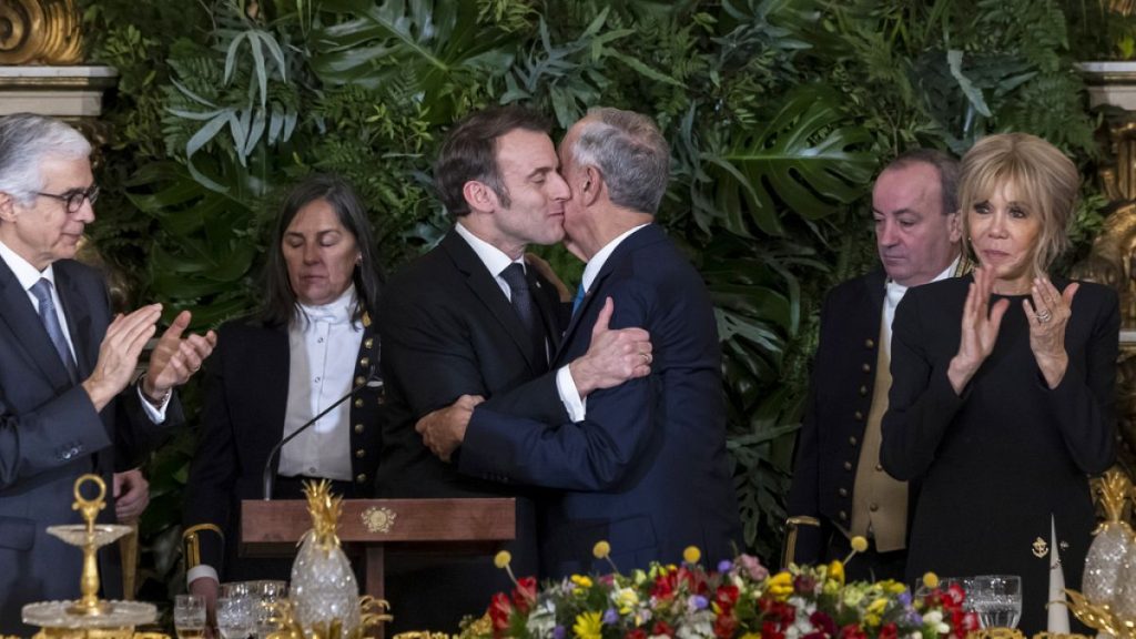 Portuguese President Marcelo Rebelo de Sousa and French President Emmanuel Macron embrace following their speeches during a state dinner at the Ajuda National Palace in Lisbon