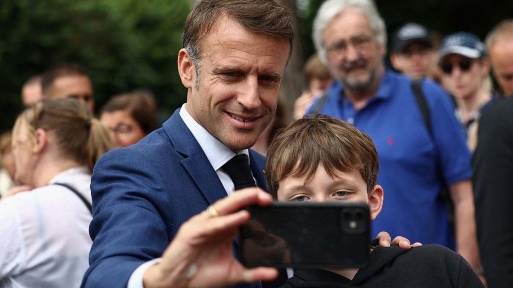 French President Emmanuel Macron takes a selfie with a boy after voting in Le Touquet-Paris-Plage, northern France, Sunday, June 30, 2024.