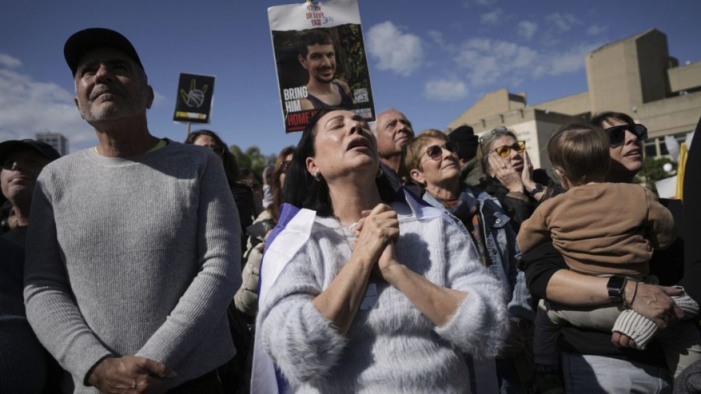People holding posters with photos of Israeli hostages react as they watch their release live on a television screen in Tel Aviv, Israel on Saturday, Feb. 8, 2025.
