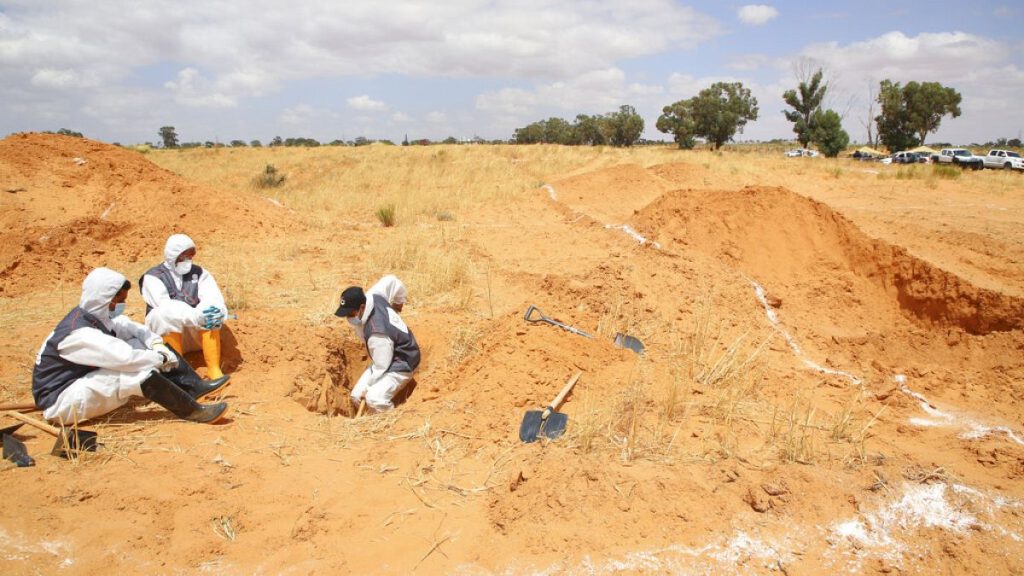 FILE - Libyan Ministry of justice employees dig out at a site of a suspected mass grave in the town of Tarhouna, Libya, Tuesday, June 23, 2020