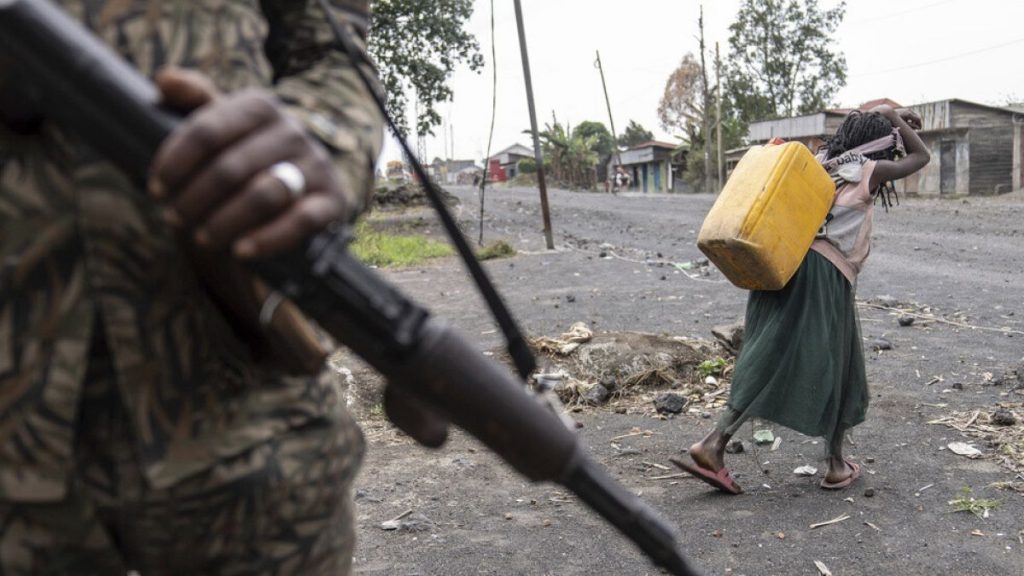 FILE: A child carrying water walks past Wazalendo forces fighting M23 rebels patrolling in Sake, Democratic Republic of the Congo, on Aug. 31, 2024.