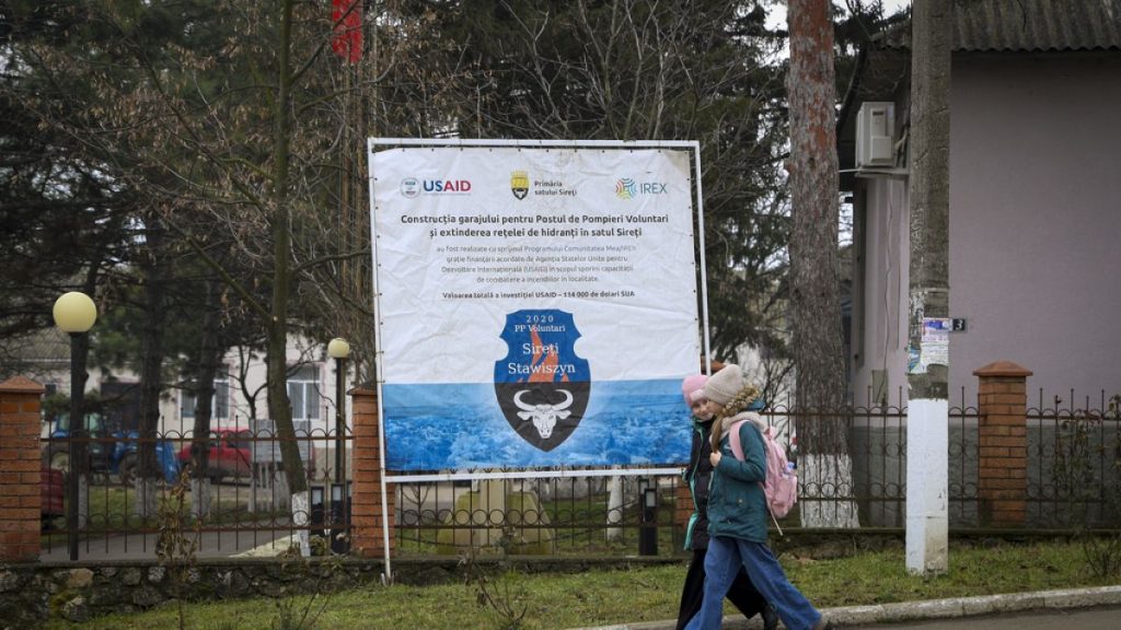 Children walk by a banner presenting a USAID-supported project in Moldova in January 2025.