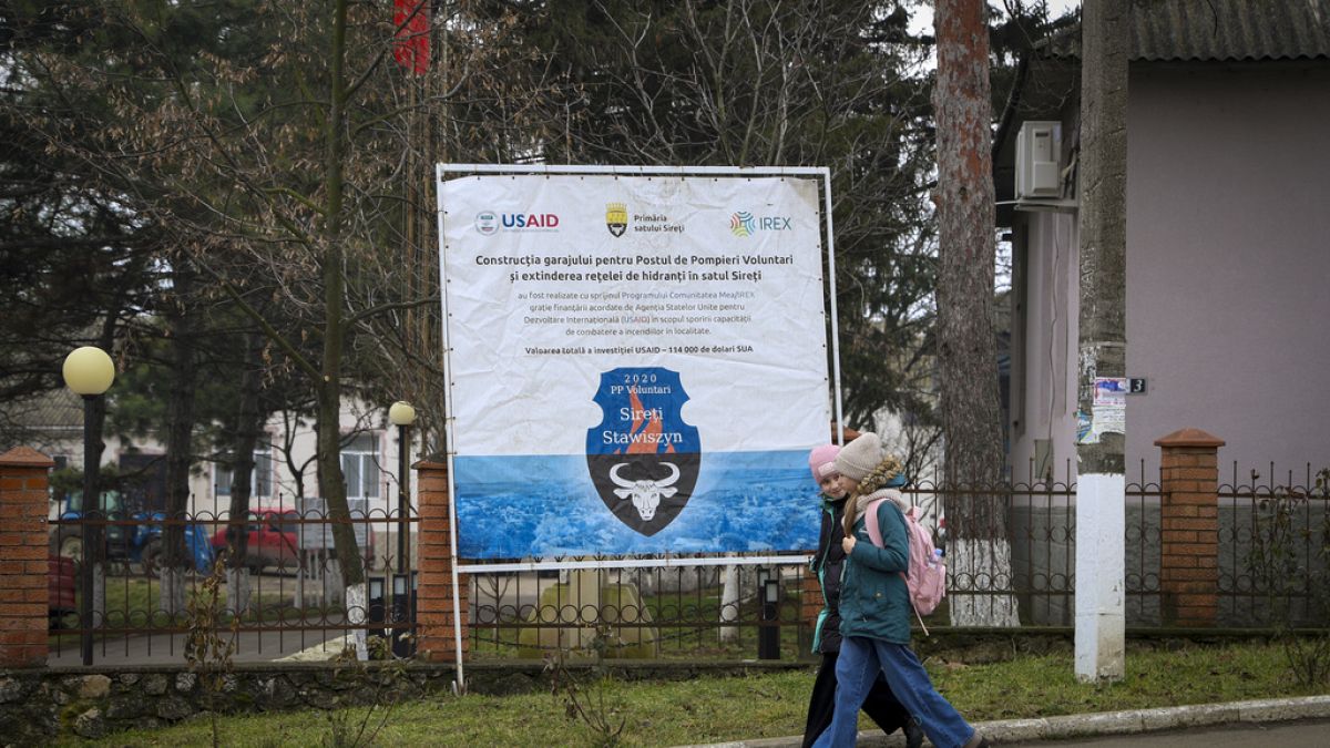 Children walk by a banner presenting a USAID-supported project in Moldova in January 2025.