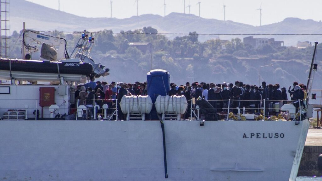 FILE - Migrants arrive in Porto Empedocle, Sicily, aboard two military ships after being transferred from the island of Lampedusa. July 27, 2020.