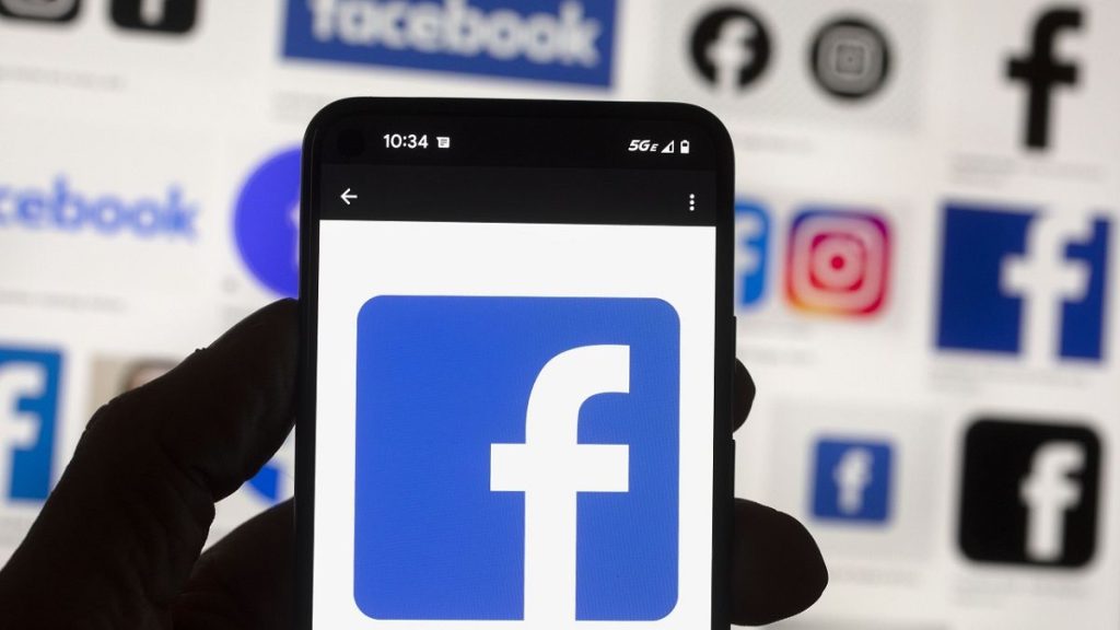 The Facebook logo is seen on a cell phone.