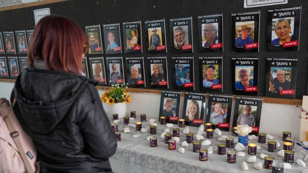 A woman looks at photos of slain hostages (bottom row, L-R) Ariel Bibas, his mother Shiri, his brother, Kfir and Oded Lifshitz, right.