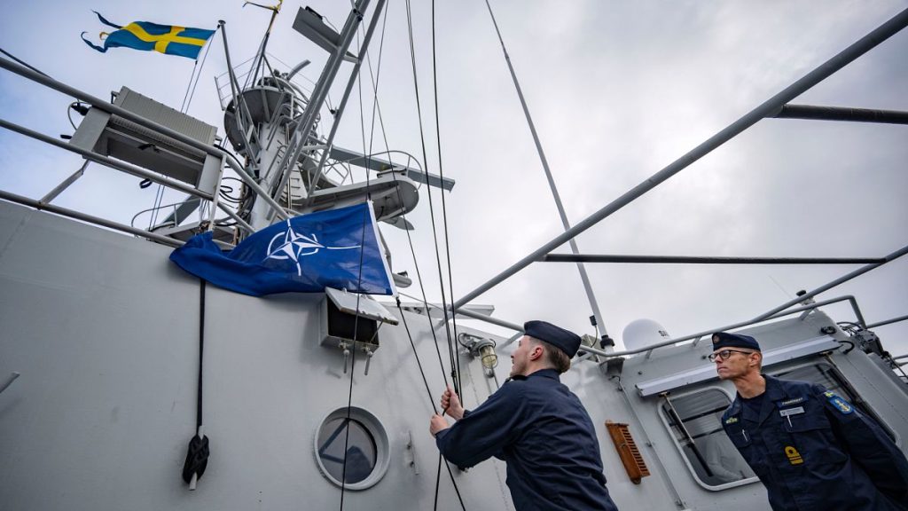 Captain Thomas Zimmerman, right, gives the order to hoist the NATO flag on the patrol ship HMS Carlskrona (P04) set sail from the naval port in Karlskrona, Sweden.
