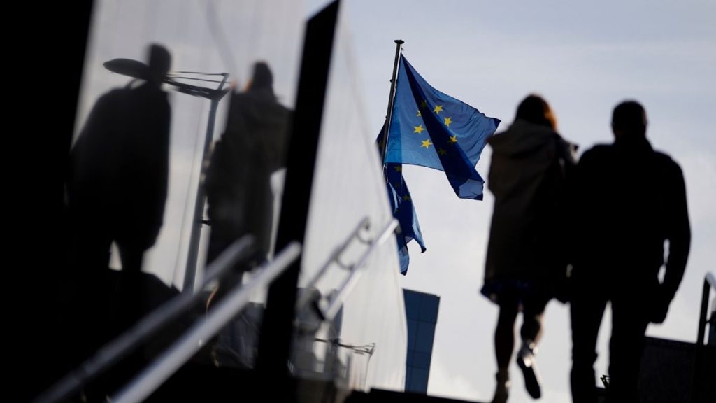 A couple walk past EU flags outside EU headquarters in Brussels, on 26 October 2021.