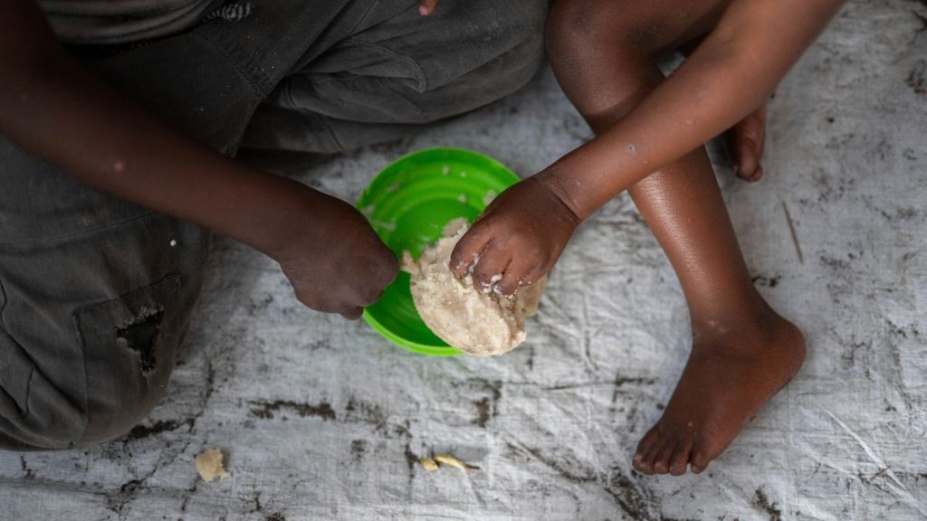 Women and children eat at a school in the DRC in February 2025.